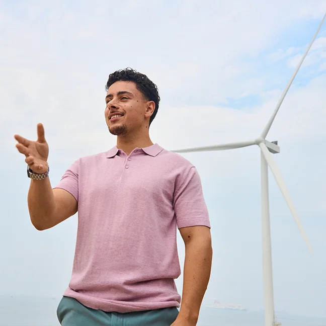 man met roze shirt en windmolen op achtergrond