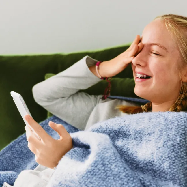 Meisje lacht en kijkt naar de telefoon.